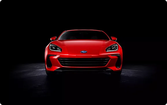 Front view of a red Subaru BRZ lit against a dark backdrop