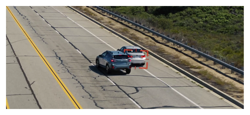An aerial view of a teal Subaru Crosstrek steering around a stopped silver sedan on a highway