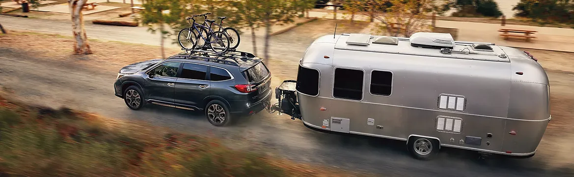 A Subaru Ascent with bikes on the roof towing a silver Airstream trailer