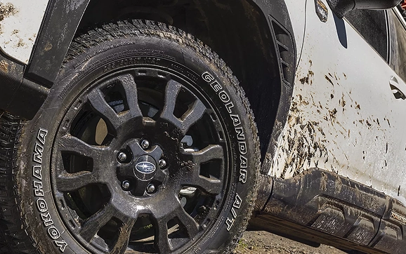 A mud-covered all-terrain tire and wheel on a Subaru Forester Wilderness