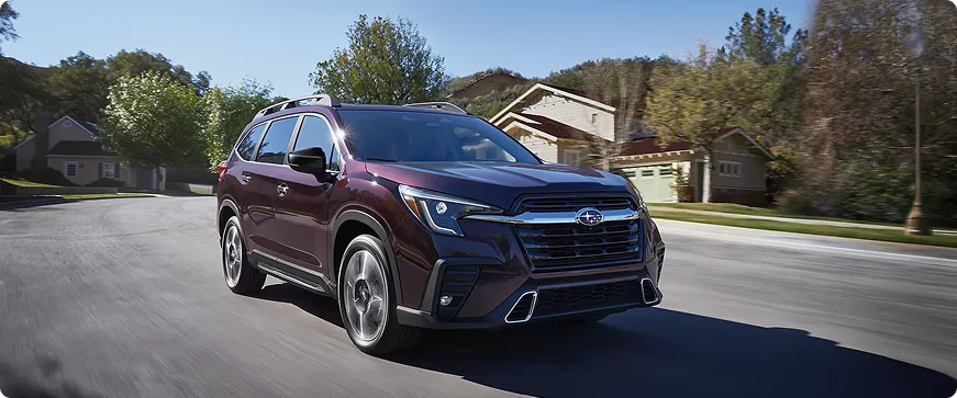 A burgundy Subaru Ascent driving through a residential neighborhood