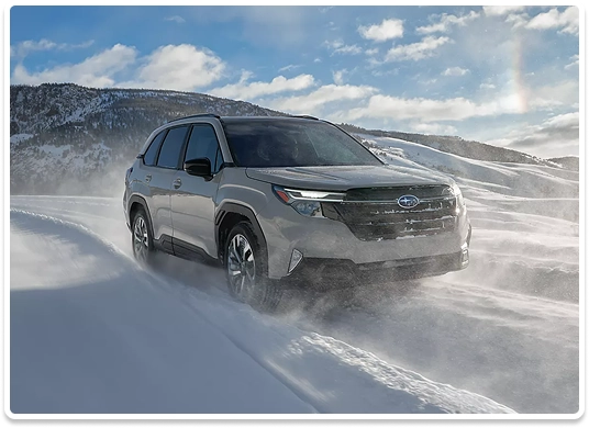 A silver Subaru Forester powering through deep snow in a mountain landscape