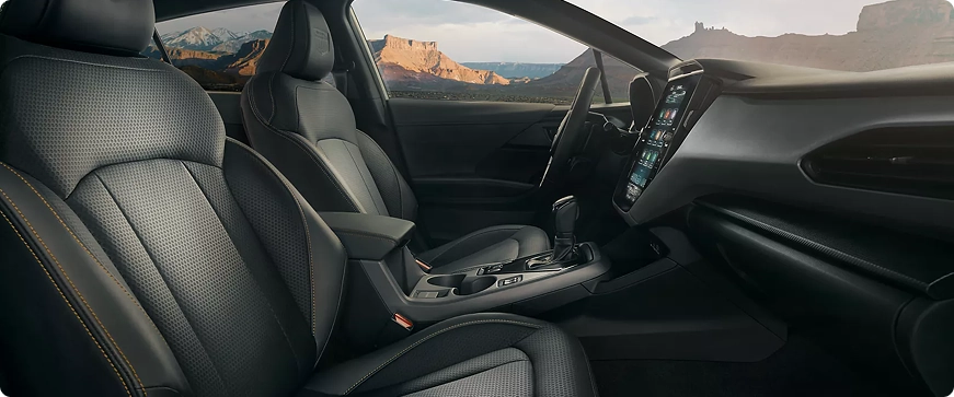The front seats, dashboard, and vertical touchscreen of a Subaru Crosstrek with a canyon view through the windshield