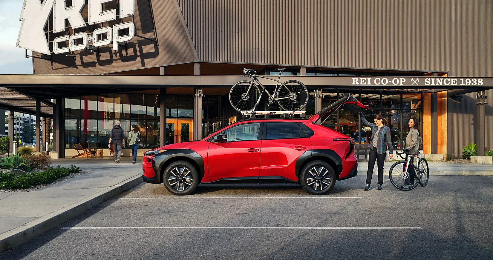 A red 2026 Subaru Solterra with bikes on the roof parked outside a co-op store