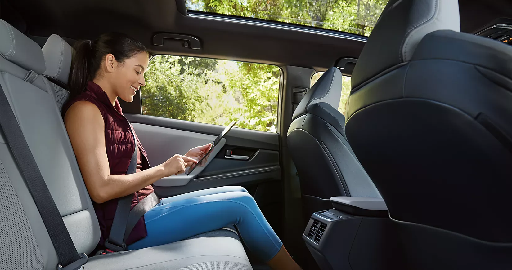 A passenger relaxing in the Solterra rear seat beneath the panoramic glass roof
