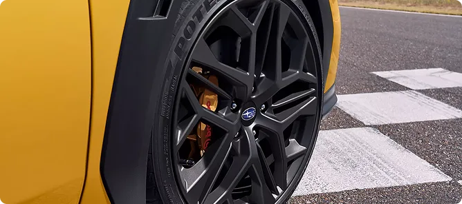Close-up of a matte black wheel and Brembo brake on the yellow WRX