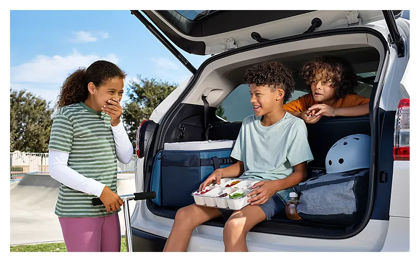 A family seated in the open rear cargo area of a white Subaru Ascent