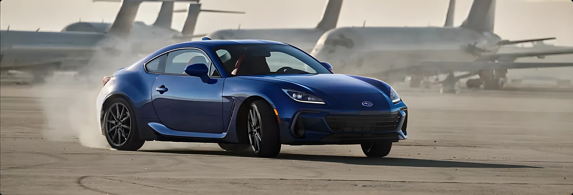 A blue Subaru BRZ sliding across an open airfield