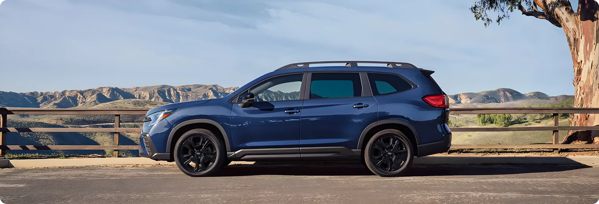 A blue Subaru Ascent Onyx Edition Touring parked on a bridge with black-finish wheels