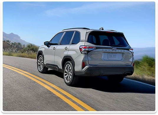 Rear view of a silver Subaru Forester on a mountain highway with the ocean in the distance