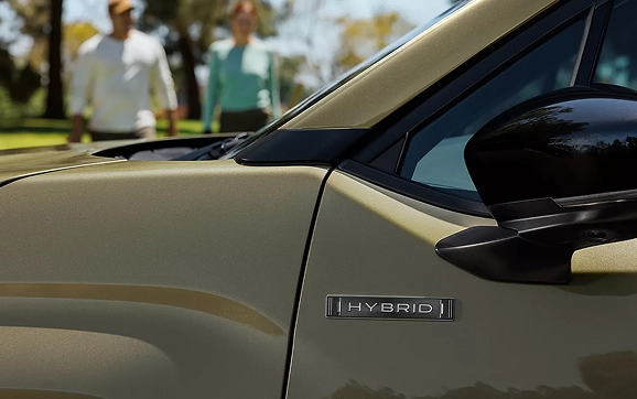 A close-up of the Wilderness badge on the front fender of a Subaru Forester as people walk by