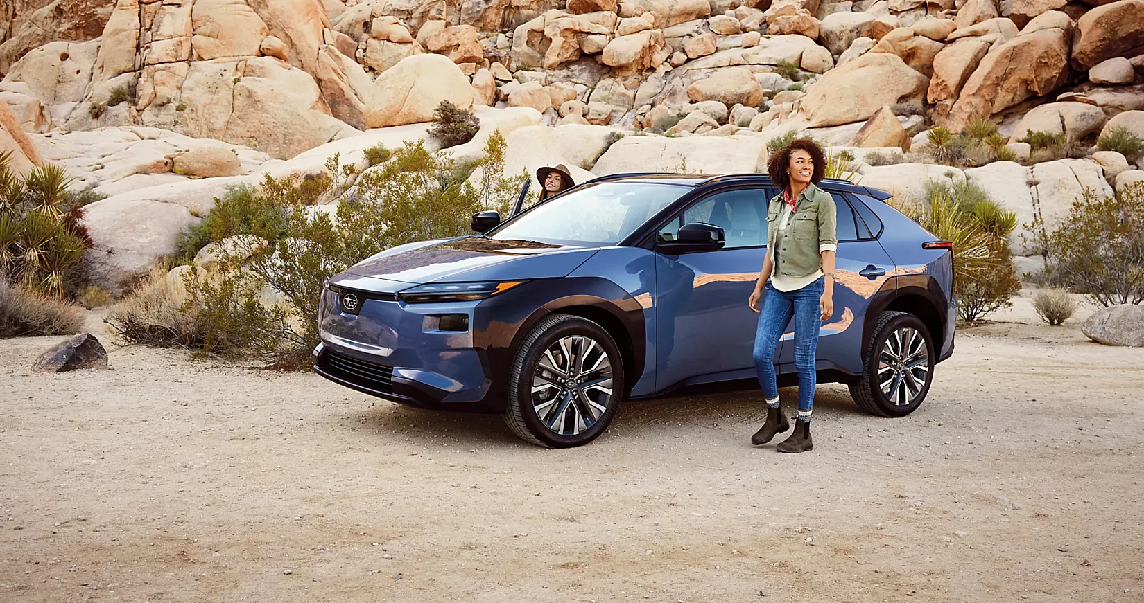 A blue 2026 Subaru Solterra parked among desert boulders
