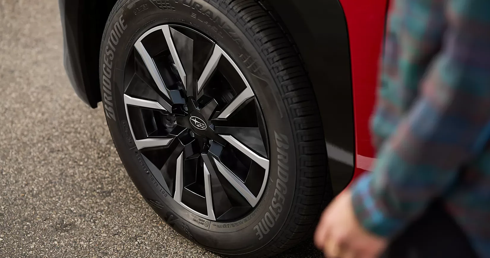 Close-up of a 2026 Subaru Solterra alloy wheel as a person walks past