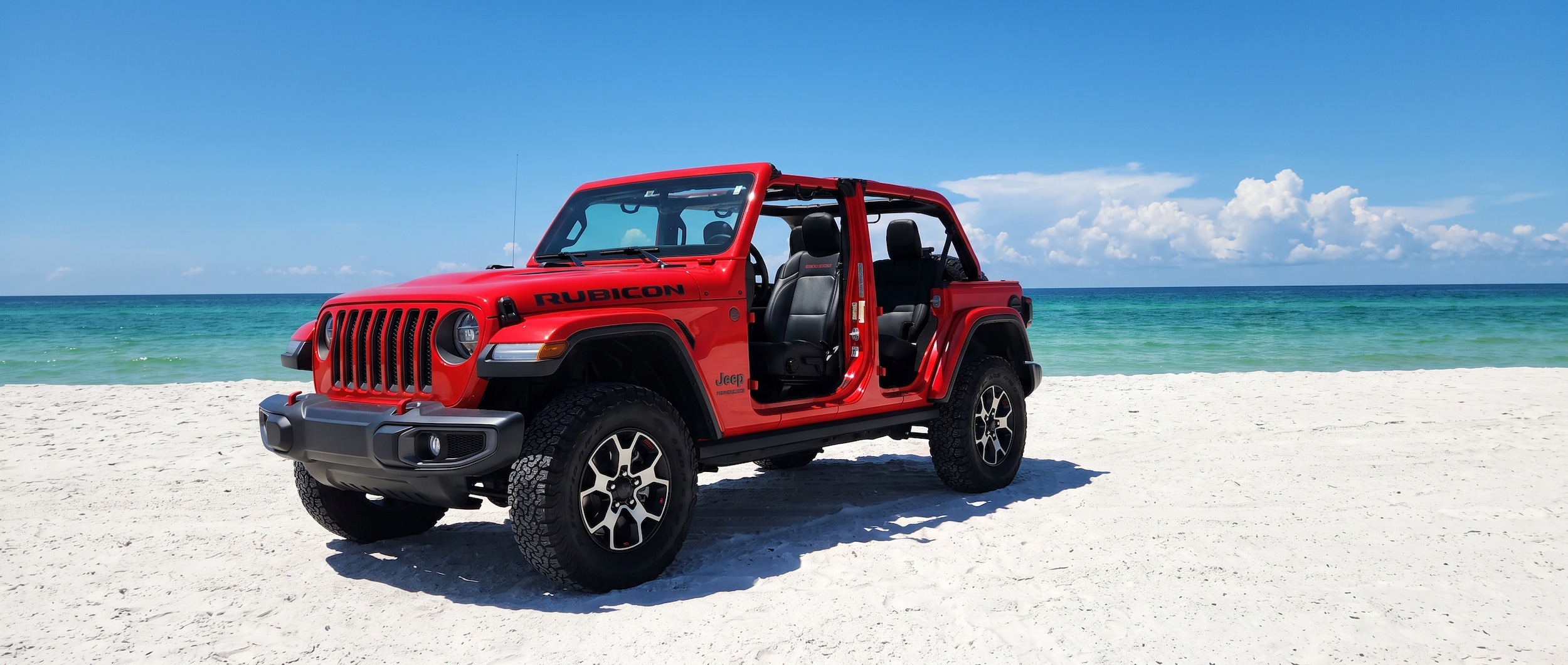 2026 Jeep Wrangler with top and doors off at a Panama City Beach Gulf Coast beach in summer sun