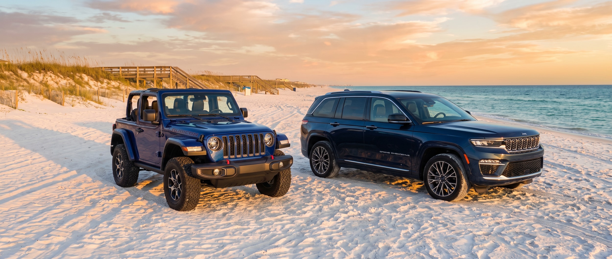 2026 Jeep Wrangler and 2026 Jeep Grand Cherokee parked on a Gulf Coast beach in Panama City Beach, Florida