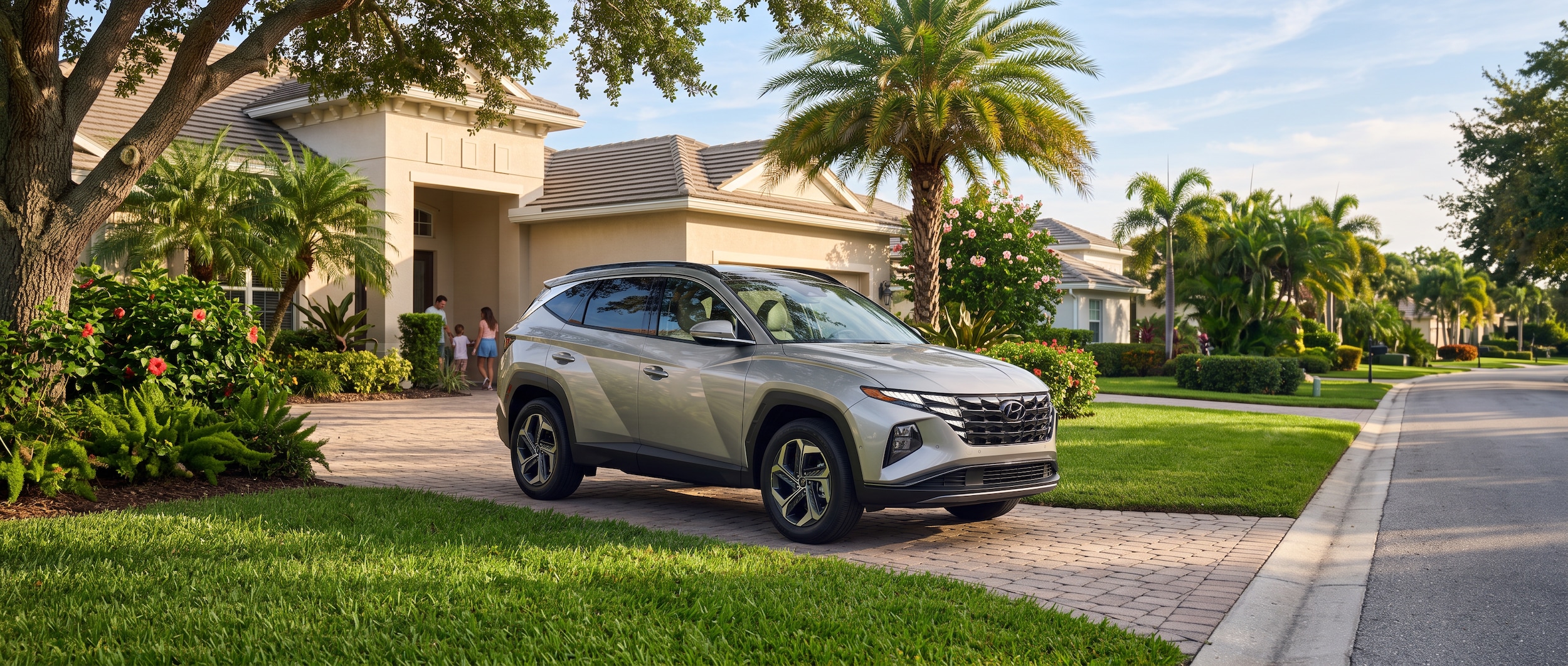 A 2026 Hyundai Tucson Hybrid in a warm silver or white finish parked in a Florida suburban neighborhood driveway, dappled late-afternoon summer sunlight, lush green lawn visible, Gulf Coast atmosphere, family-ready compact SUV stance