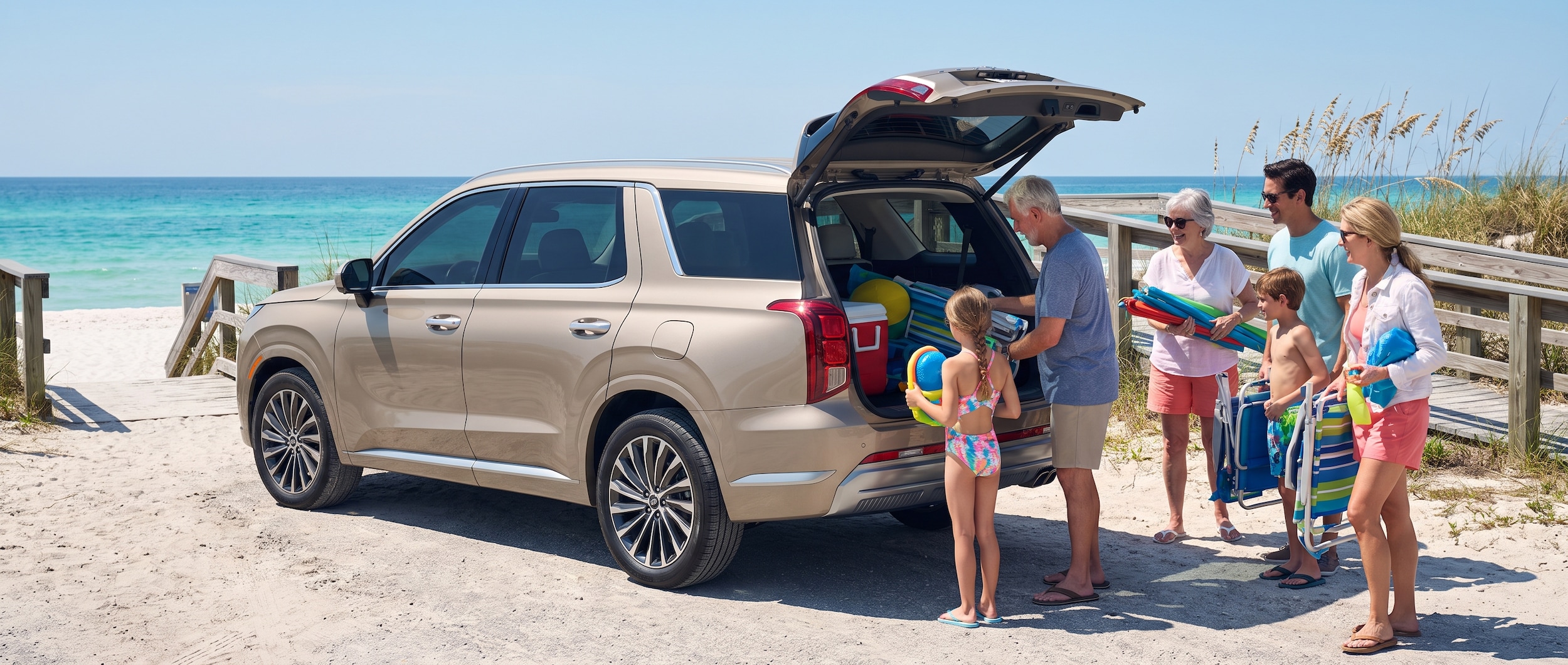 A 2026 Hyundai Palisade parked at a Gulf Coast beach access point near Panama City Beach, Florida, with turquoise water visible in the background, multiple generations of a family unloading beach gear from the open rear hatch on a bright summer day.