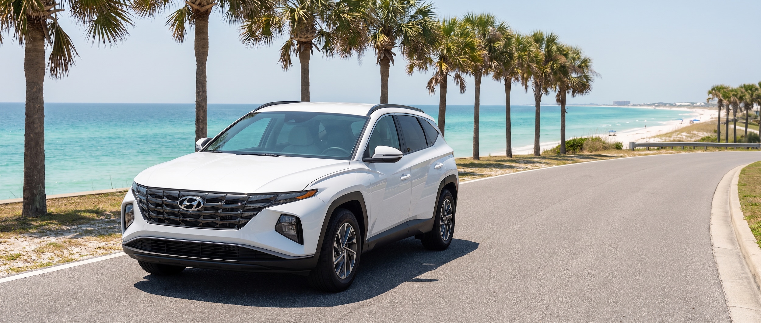 A 2026 Hyundai Tucson in white parked on a sun-drenched coastal road with palm trees and turquoise Gulf water visible in the background, evoking a summer Panama City Beach drive