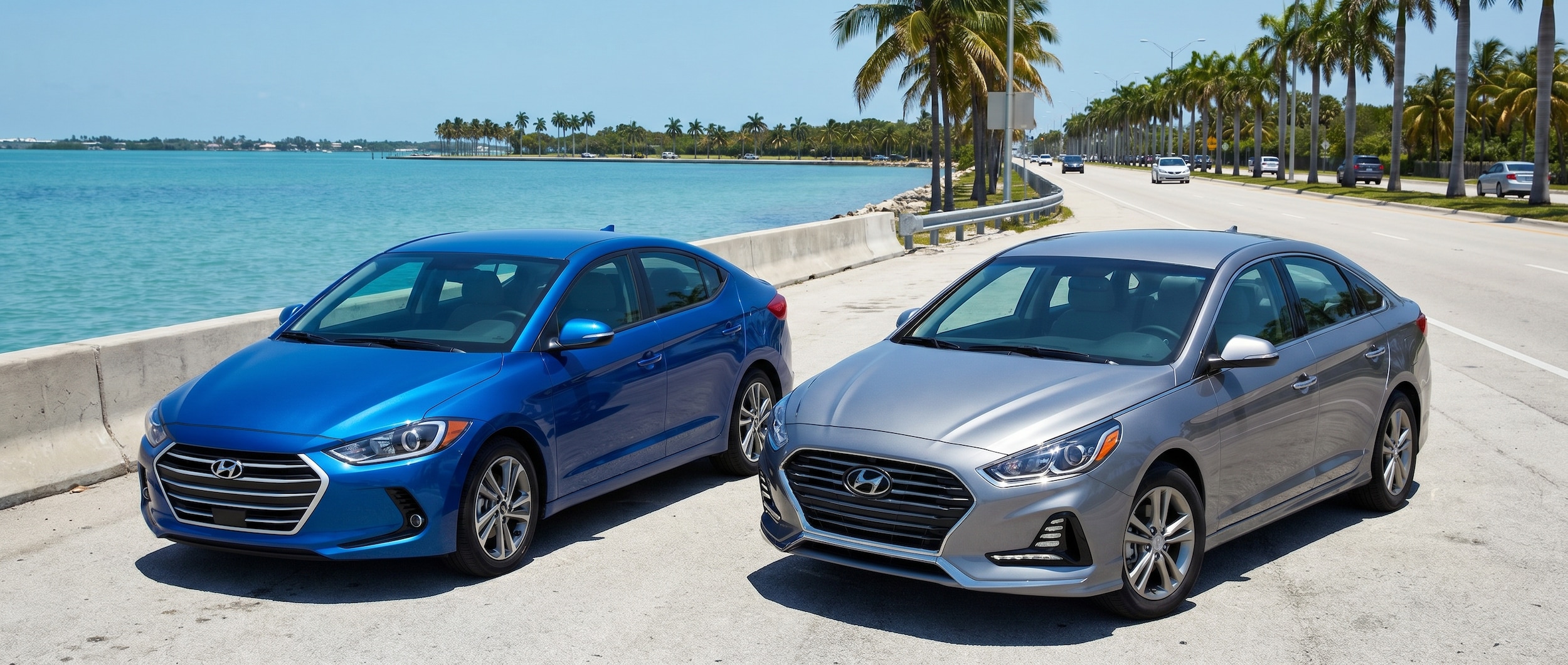 Two 2026 Hyundai sedans -- one compact, one midsize -- parked side by side near a coastal Florida causeway at midday summer light, with a palm-lined boulevard visible in the background suggesting a Gulf Coast commute setting.