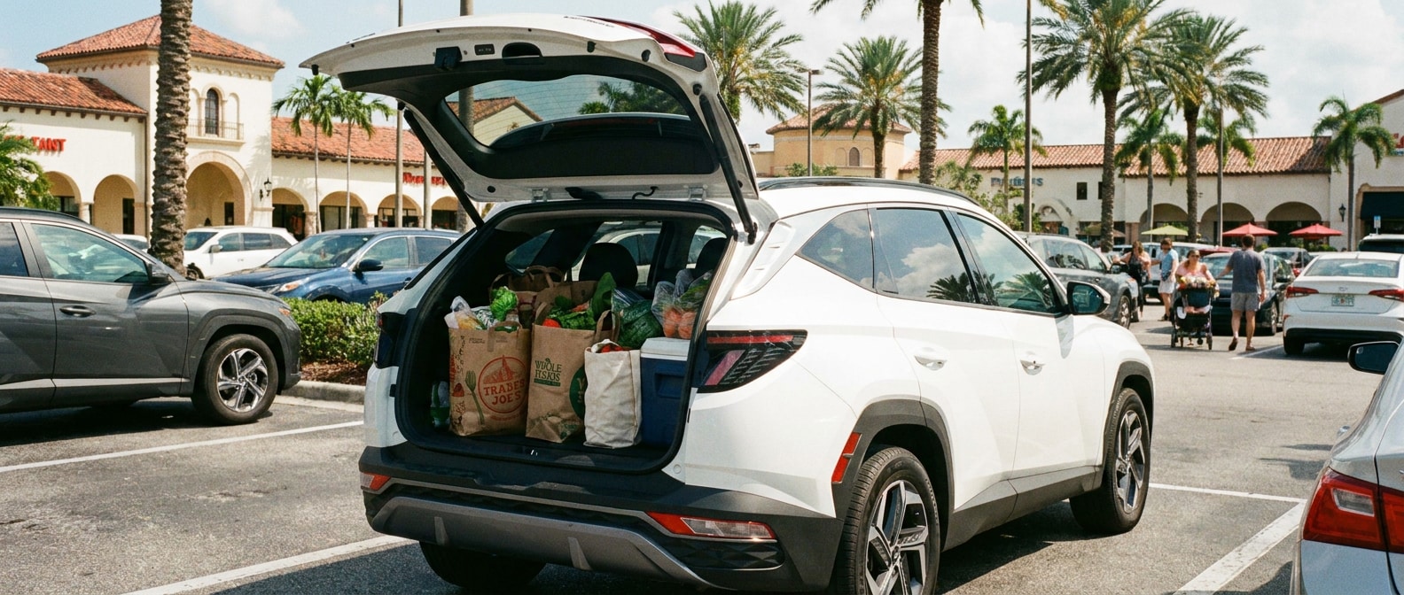 2026 Hyundai Tucson Hybrid rear liftgate open with groceries loaded at a sunny Florida shopping center