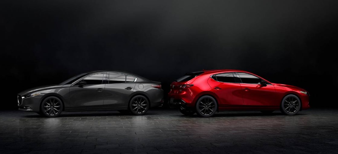 Black MAZDA3 Sedan parked next to a red MAZDA3 Hatchback.