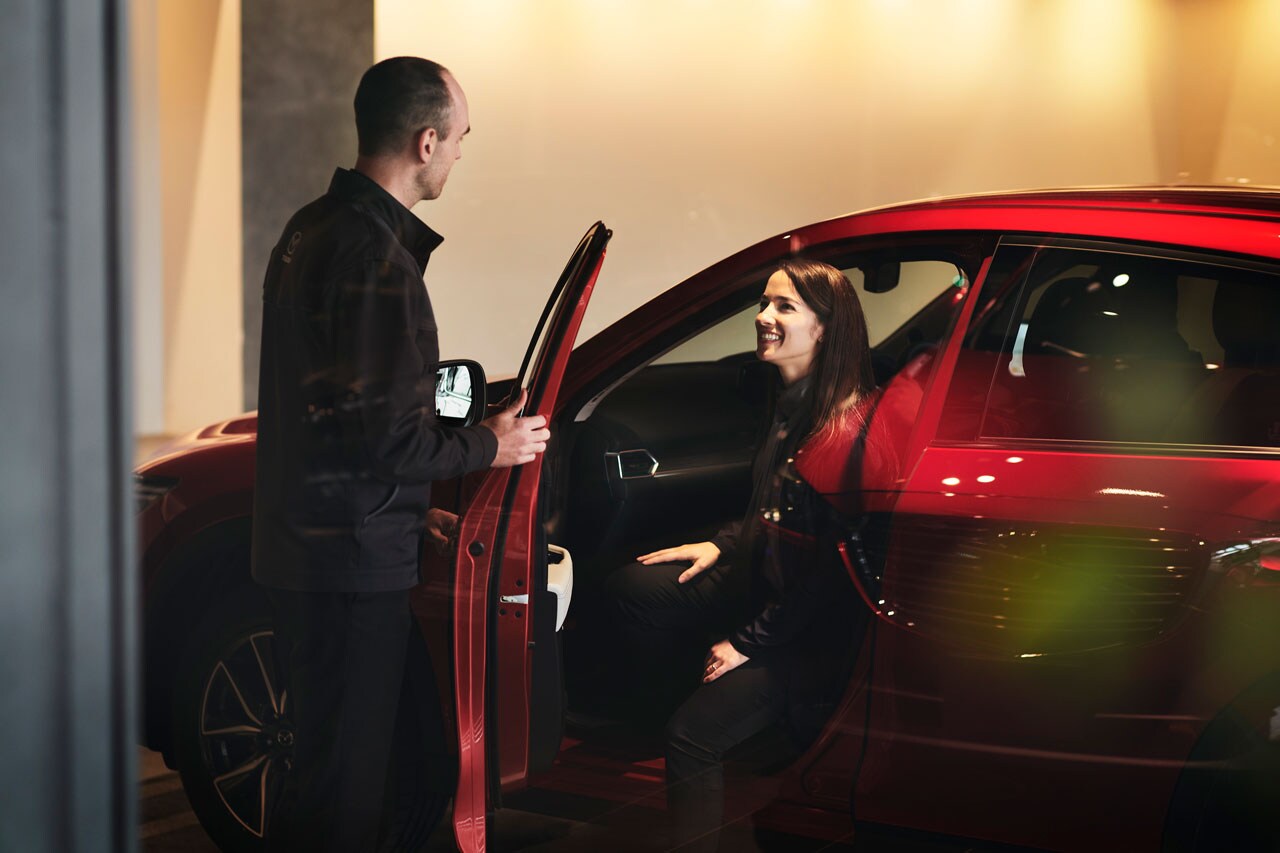 Mazda sale advisor assisting customer with vehicle inspection at Berglund Mazda in Salem VA.
