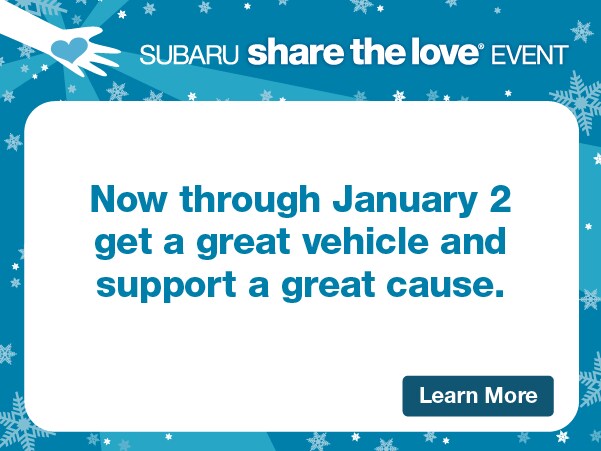  Group of individuals making a heart shape with their hands standing in front of a Subaru Store.