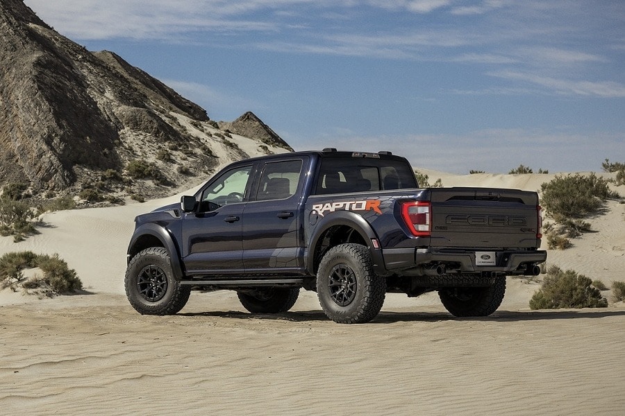 A navy 2023 Ford F-150 Raptor driving in a desert.jpg