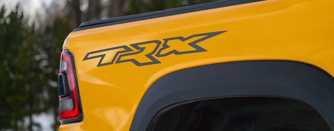A close up shows the TRX badge on a yellow 2023 Ram 1500 TRX Havoc Edition.