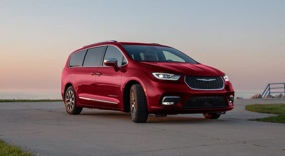 A red 2024 Chrysler Pacifica Hybrid Pinnacle is parked on a concrete lot.