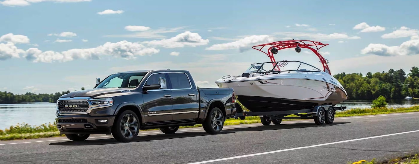 A grey 2024 Ram 1500 is shown from the side while towing a boat after leaving a Ram dealer near North Adams.