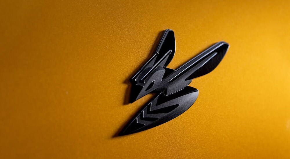 A close-up shows the badge of a yellow 2024 Dodge Hornet.