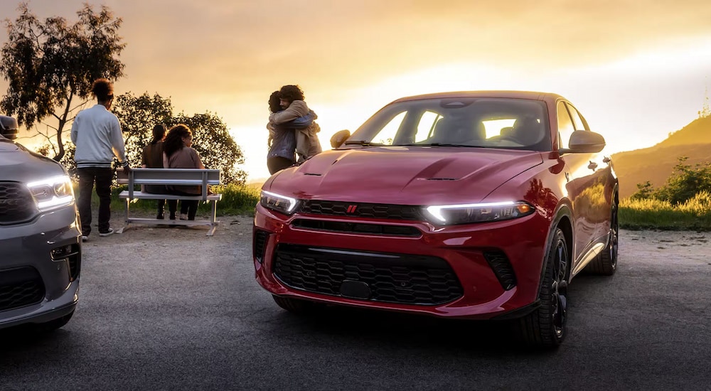 A red 2024 Dodge Hornet parked next to people picnicking on a mountain.