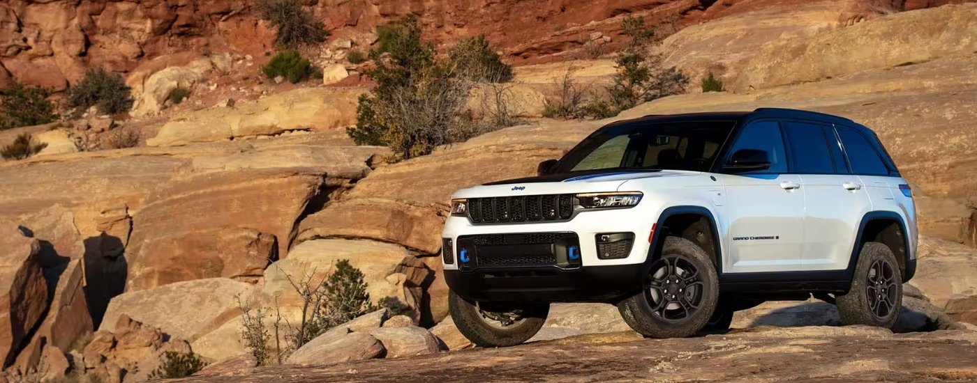 A white 2025 Jeep Grand Cherokee Trailhawk 4xe is shown from the front at an angle.