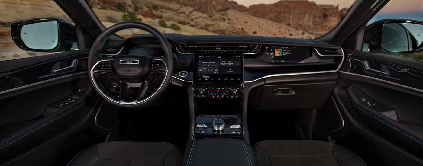 The black interior of a 2025 Jeep Grand Cherokee for sale is shown from the center console.