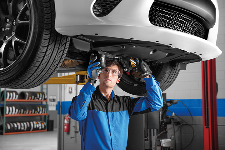 Mopar service technician under a vehicle on the lift installing an oil filter