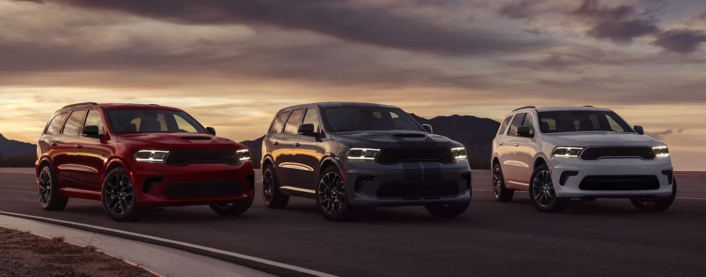 A red a grey and a white 2024 Dodge Durango are shown parked next to each other.