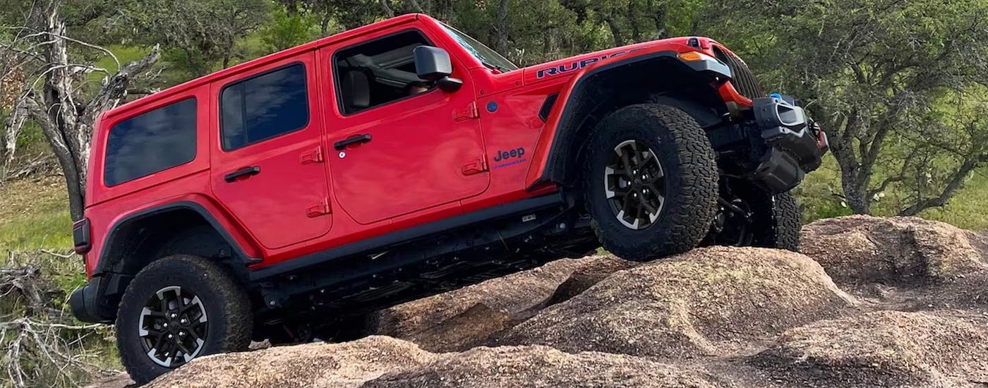 A red 2024 Jeep Wrangler Unlimited Rubicon 4xe is shown from the side after leaving a Jeep dealer near Pittsfield.