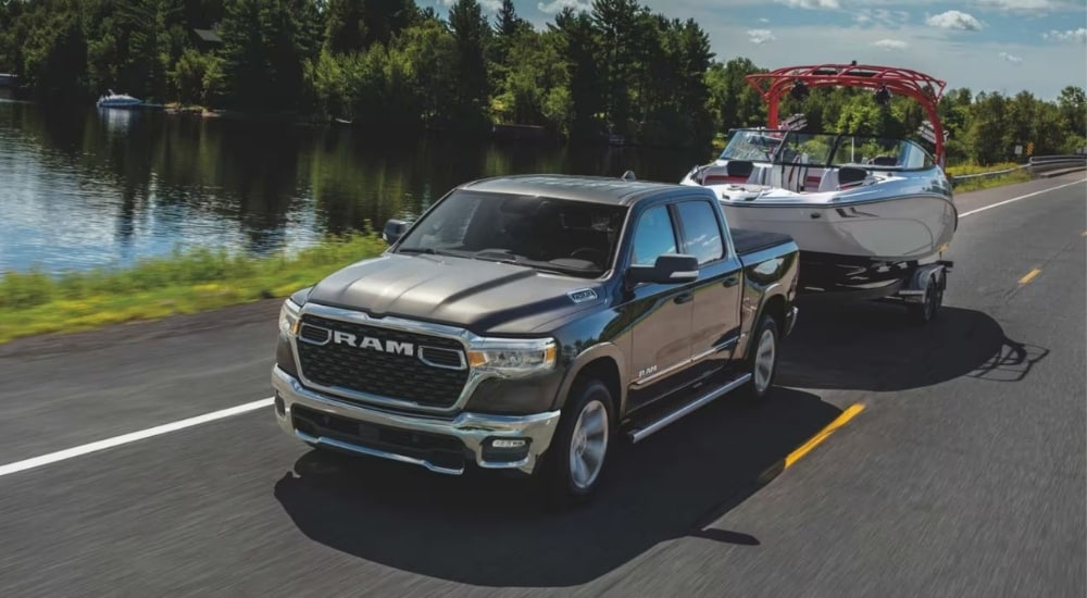 A silver 2025 Ram 1500 Big Horn towing a boat on the highway.