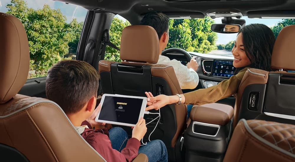 The tan interior of a 2024 Chryslre Pacifica is shown from the rear seats.