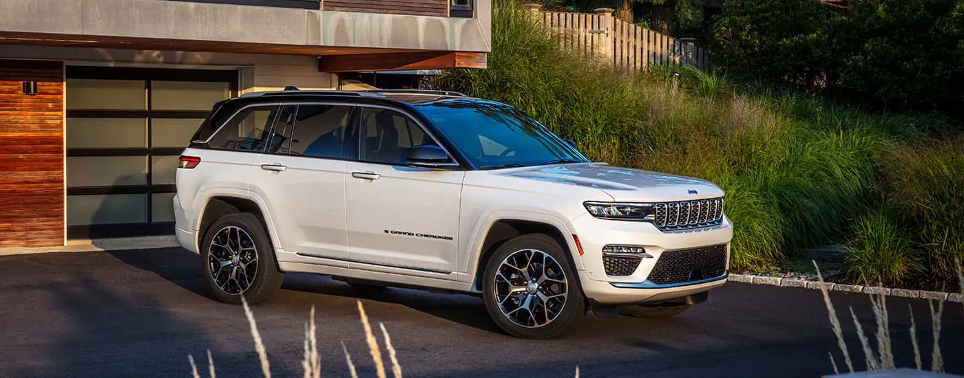 A white 2024 Jeep Grand Cherokee is shown parked in a driveway.