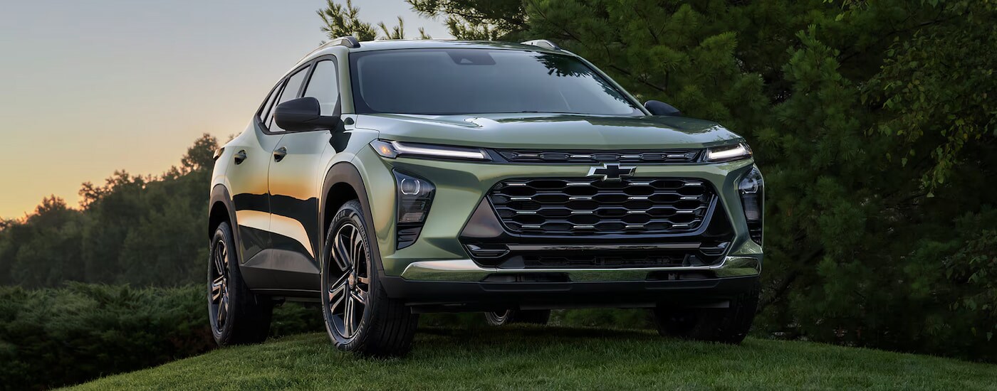 A light green 2025 Chevy Trax ACTIV parked on a grassy hill.