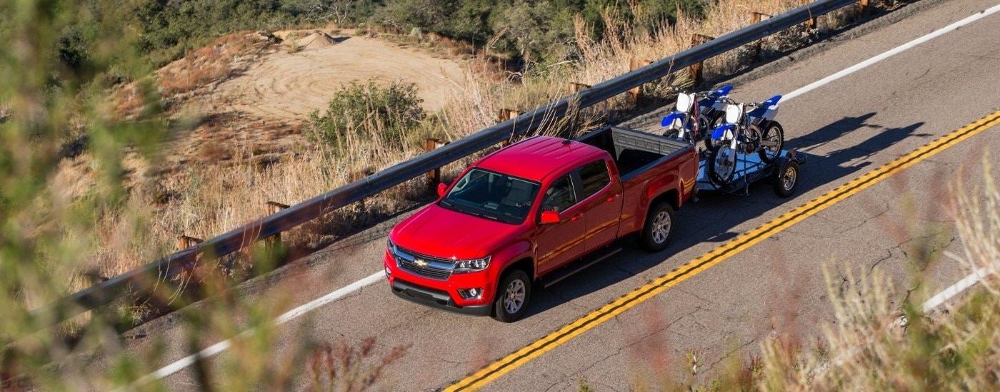 A red 2015 Chevy Colorado for sale towing dirtbikes.