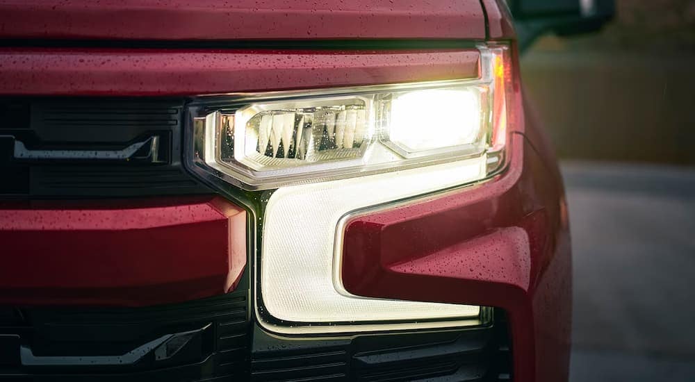 A close-up of the headlight on a red 2024 Chevy Silverado 1500 RST.