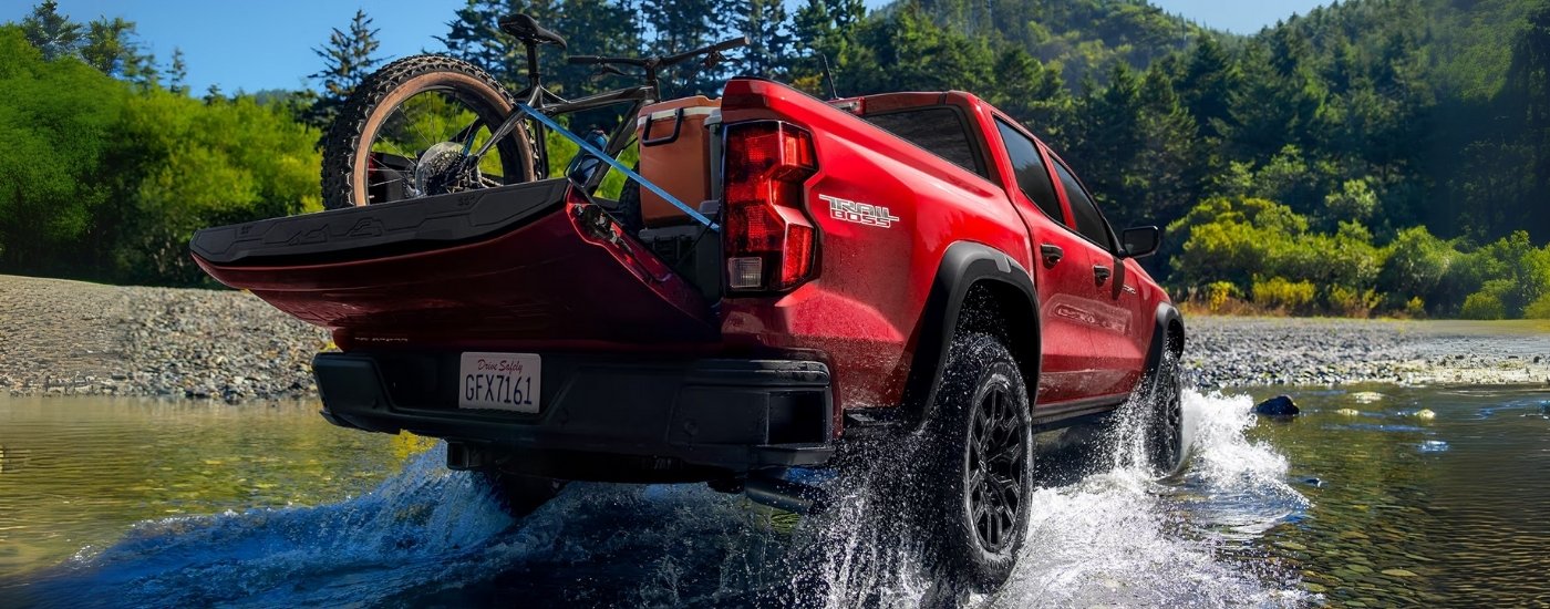 A red 2024 Chevy Colorado for sale near Pittsfield is driving through a creek.