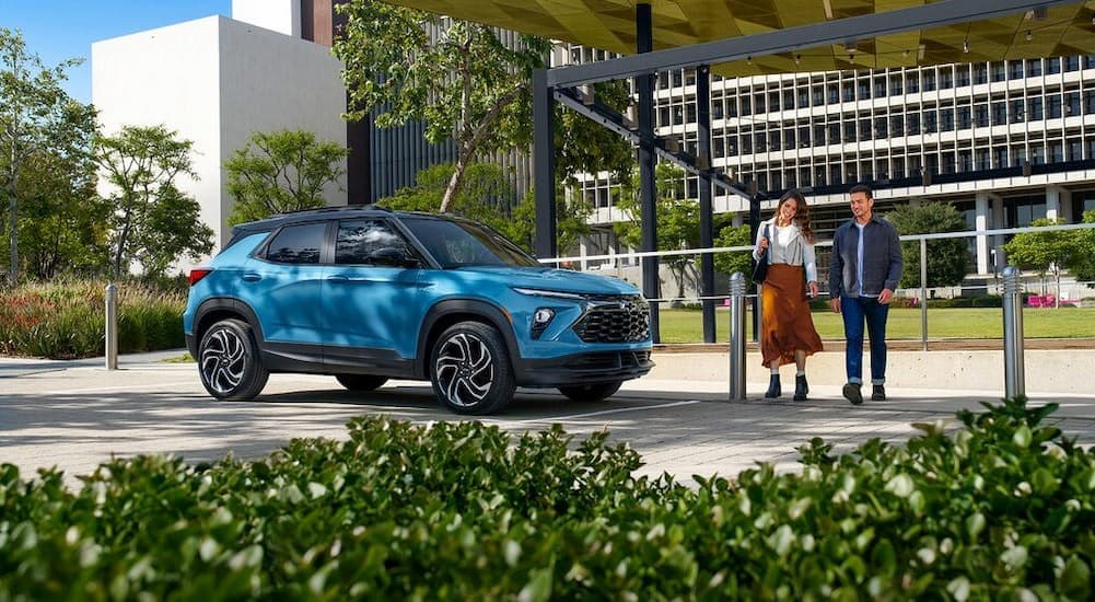 A blue 2025 Chevy Trailblazer RS is shown parked near two people walking.