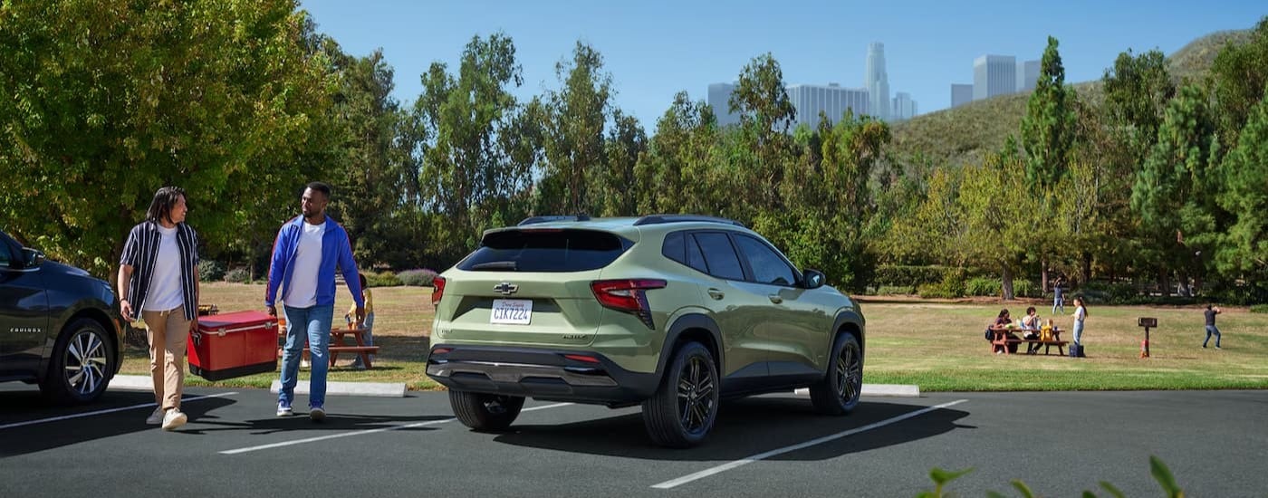 A green 2025 Chevy Trax ACTIV is shown parked near a grassy common area.