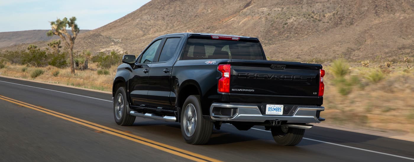 A black 2024 Chevy Silverado 1500 LT is shown from the rear at an angle.