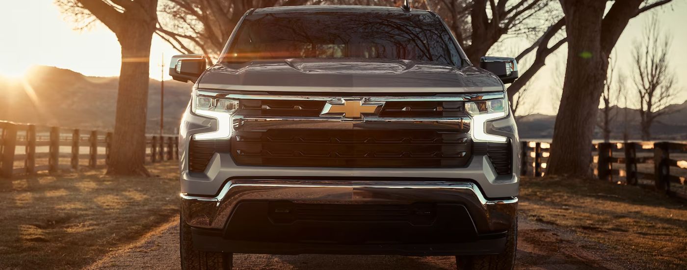 Close-up of the grille on a silver 2024 Chevy Silverado 1500 LT Z71 parked on a farm.