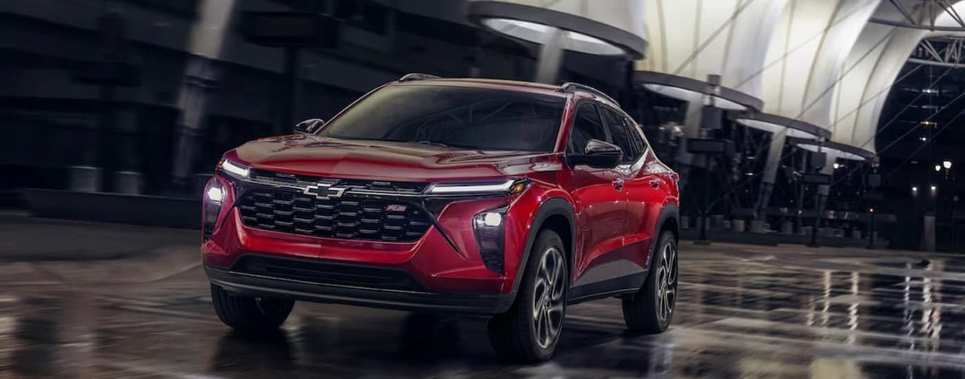A red 2025 Chevy Trax RS is shown driving on a wet surface.